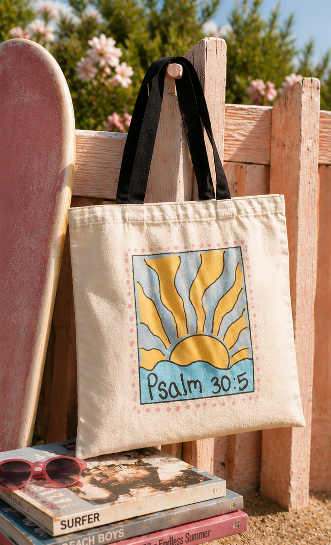 Faith-inspired Psalm 30:5 sunrise tote bag photographed beside a skateboard and beach fence in bright coastal sunset lighting.