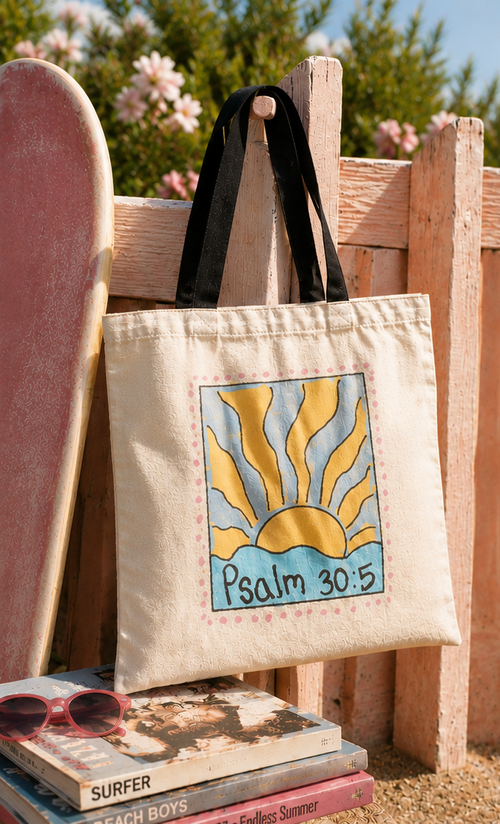 Faith-inspired Psalm 30:5 sunrise tote bag photographed beside a skateboard and beach fence in bright coastal sunset lighting.